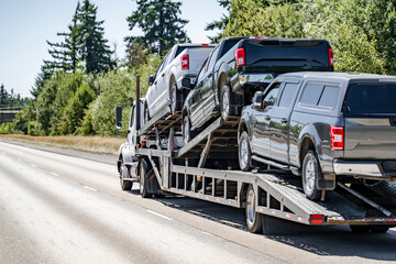 Big rig powerful car hauler semi truck transporting pick up trucks on the modular semi trailer...