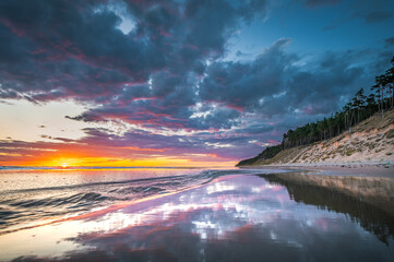 Baltic sea in colorful sunset colors with storm clouds. Turquoise water with waves, and sandy...