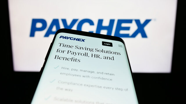 Stuttgart, Germany - 08-06-2023: Mobile phone with webpage of US outsourcing company Paychex Inc. on screen in front of business logo. Focus on top-left of phone display.