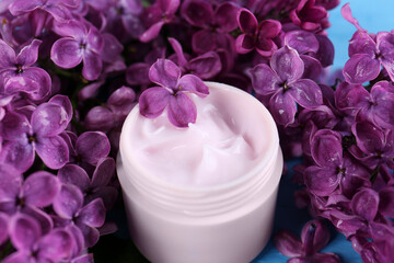 Obraz na płótnie Canvas Jar of cream and lilac beautiful flowers as background, closeup