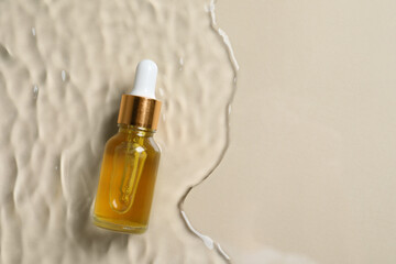 Naklejka premium Bottle of cosmetic oil in water on beige background, top view. Space for text