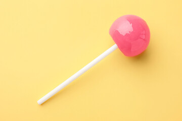 Tasty lollipop on yellow background, top view