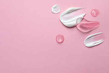 Samples of transparent gel and white cream on pink background, flat lay. Space for text