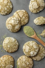 Tasty matcha cookies and wooden spoon of powder on grey table, flat lay