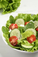 Delicious salad in bowl on white table, closeup