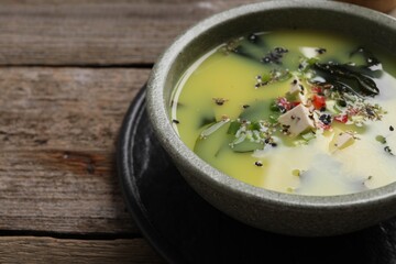 Bowl of delicious miso soup with tofu on wooden table, closeup. Space for text