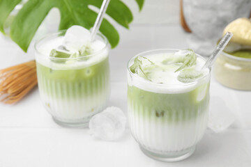 Obraz na płótnie Canvas Glasses of tasty iced matcha latte on white tiled table