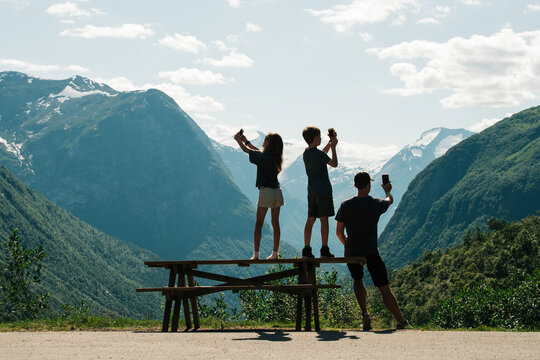 family taking pictures with their phones of a beautiful view in Norway