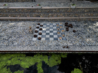 recreation terrace in the park on the waterfront. the tiles in the checkerboard pattern and the blocks represent the game pieces of checkers. drafts table game. large scale. granite paving.