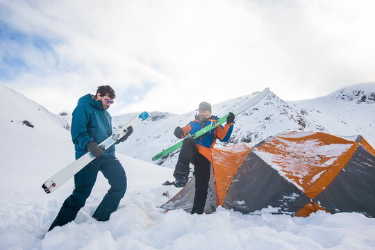 Two skiers use their skis as air guitars, jam session at basecamp
