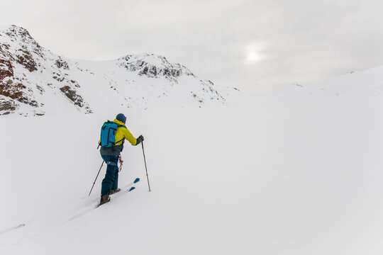 Rear view of man ski touring up mountain in B.C. Canada