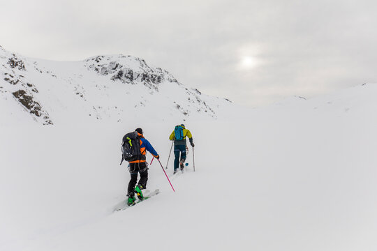 Rear view of two skiers touring up glacier in remote location