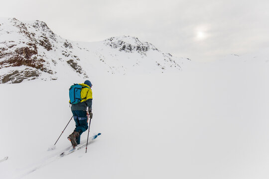 Rear view of man ski touring up glacier in B.C. Canada