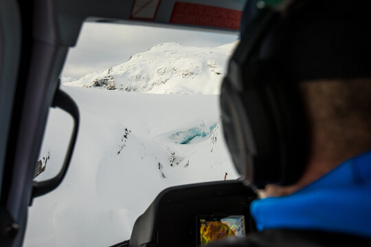 rear view of passenger looking out window of helicopter at glacier