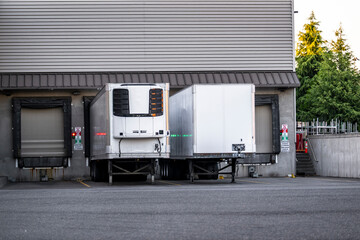 Refrigerated and dry van semi trailers unloading delivered cargo standing in store dock with semi...