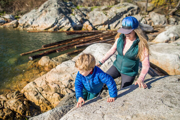 Mother and son climb on rocks near the shoreline, Vancovuer.