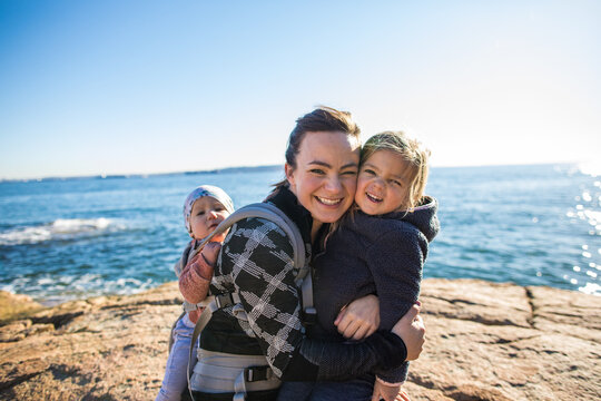 Portrait of young attractive mother with her two kids at the ocean.