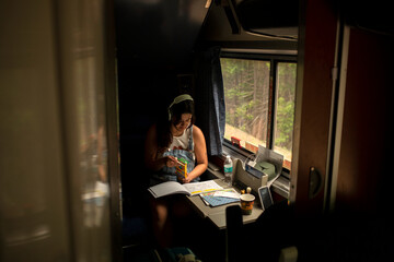 Young woman riding passenger train with coloring book