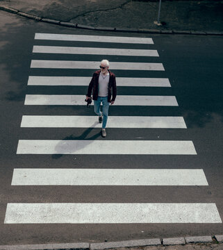 Albino man with a camera in his hands crossing the road