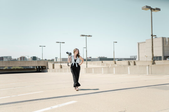 A woman walking through a parking garage holding a digital camera