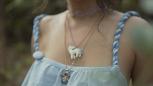 Unicorn and floral necklace around a young woman's neck. Backward dolley shot
