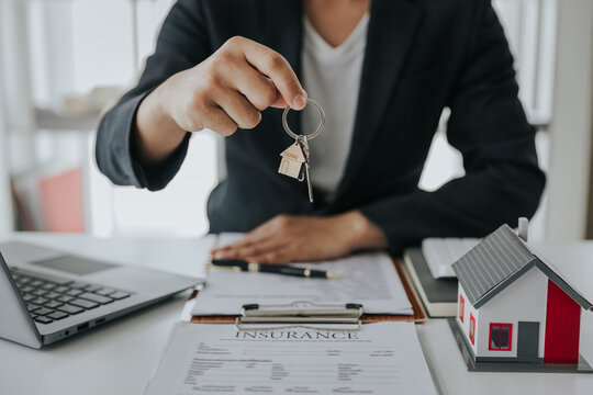 Male businessman or real estate agent holding house key for his client after signing contract in office concept for real estate Moving house or renting property