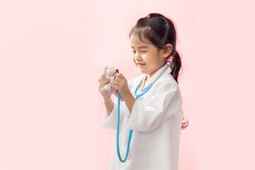 Asian girl holding a stethoscope Wearing a white medical gown on a pink background