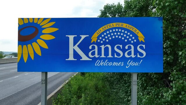 Kansas Welcomes You road sign. Aerial establishing shot of welcome to Kansas landmark along interstate highway. Ad Astra Per Aspera.