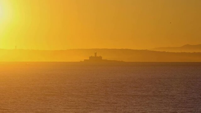 Capture the Bugio Lighthouse charm at golden hour. Situated on a rocky island amidst the Atlantic Ocean near Oeiras coast and the Tejo River, in Lisbon, Portugal, on a sunny day.