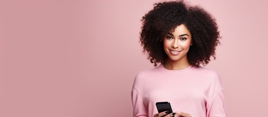 Curly haired woman blogger poses with phone on pink background technology and social media