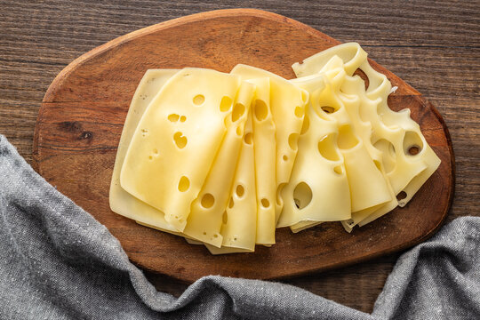 Slices of cheese on cutting board. Top view.