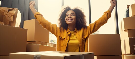Enthusiastic black woman creating a checklist on moving day joyful female raising pencil and searching for space surrounded by cardboard boxes at home - obrazy, fototapety, plakaty