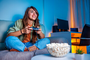 Woman having fun playing video games at home late at night