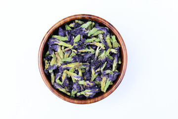 Dried blue butterfly pea flower in a wooden bowl on white background top view 