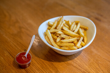 A bowl of crispy French fries and ketchup