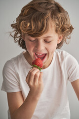 Happy boy eating strawberry at home