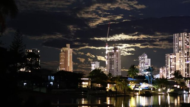 Time lapse of the moon rising over Broadbeach, QLD, Australia with a scenic view of buildings and a canal.