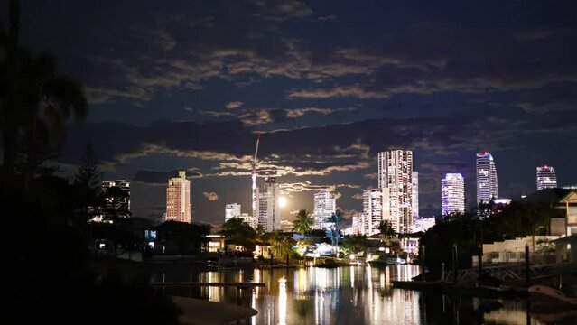 Time lapse of the moon rising over Broadbeach, QLD, Australia with a scenic view of buildings and a canal.
