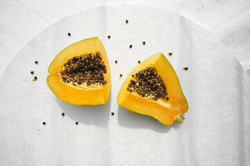 Ripe papaya pieces with seeds on table