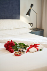 Gift and red roses and cup of coffee on bed