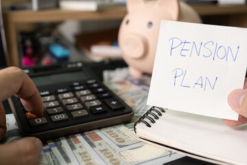 Paper note with text PENSION PLAN with stationery on desk. Pension Plan. Retirement concept. Pension calculation concept. copy space for text. Piggy bank.