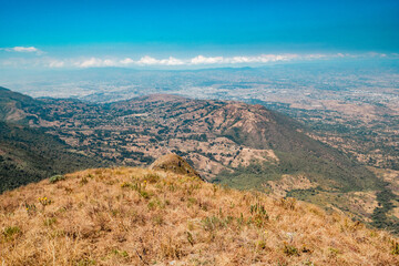 Fototapeta na wymiar View of a valley against mountains seen from Mbeya Peak, Mbeya Mountain range in Mbeya Region, Tanzania