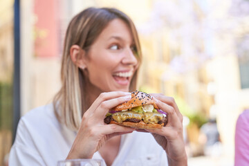 Happy woman eating appetizing hamburger
