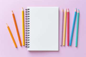 Top view of empty notebook with colorful crayon pencils on pastel background