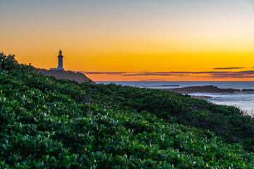 Fototapeta na wymiar Sunrise seascape with lighthouse in the distance