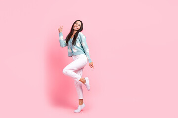 Fototapeta na wymiar Full length photo of funky cheerful woman dressed blue cardigan showing v-sign empty space isolated pink color background