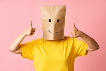 Woman wearing paper bag on head with smile emoticon icons face showing thumbs up