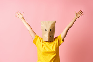 Woman with happy smile on the paper bag on head celebrating success with winner gesture