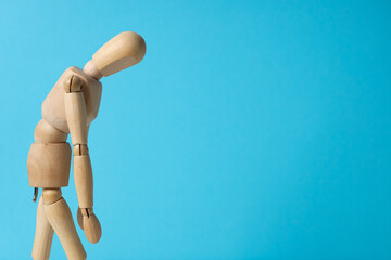 Figurine of sad wooden man on blue background, space for text