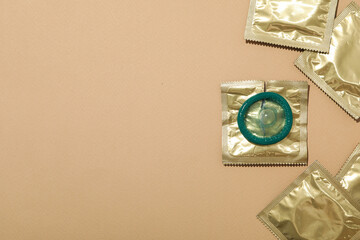 Condoms in a golden wrapper on a light background close-up, place for text